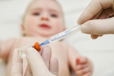 Doctor holds syringe to vaccinate  6 months baby with injection