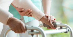 Pflegekraft hilft aelterem Menschen beim Gehen