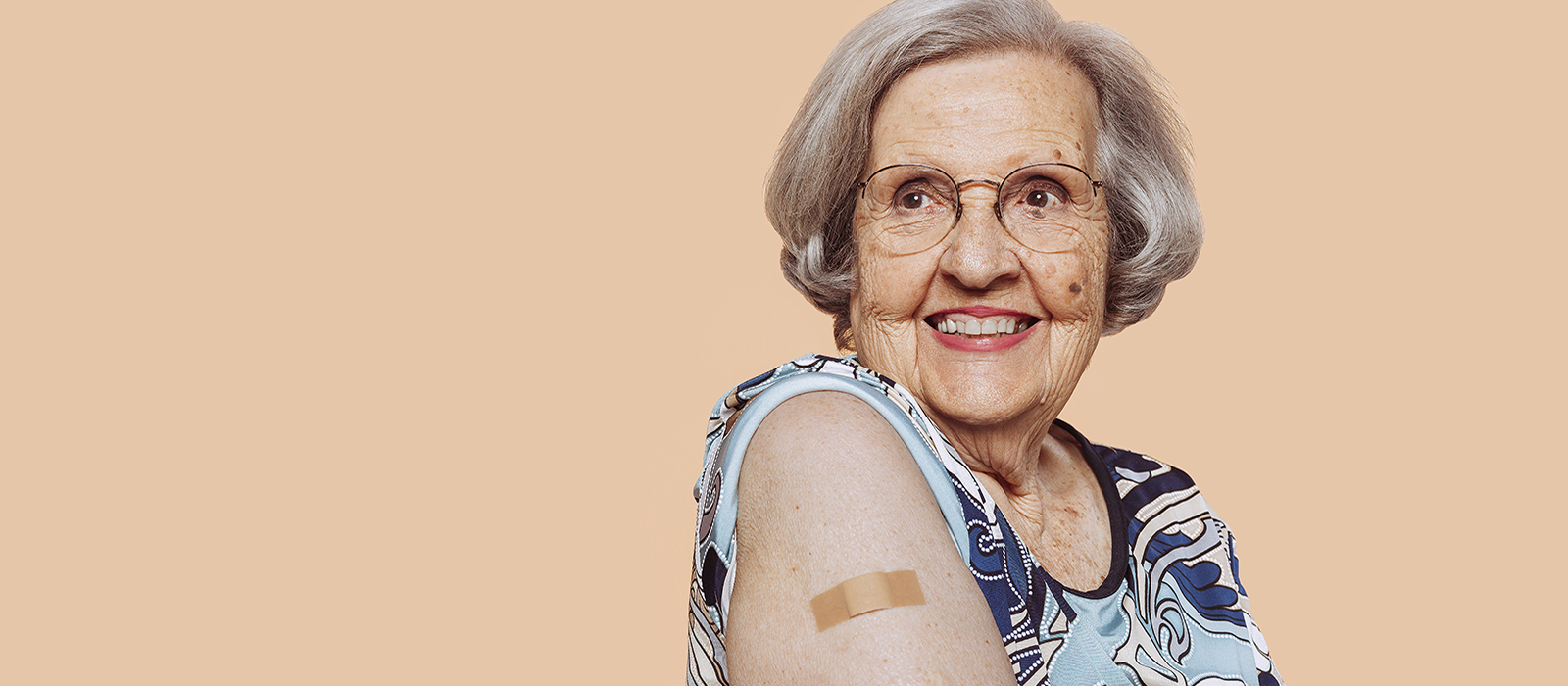 Ältere Frau zeigt auf Ihre Plaster nach der Impfung